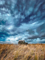 Green landrover defender oversized suv truck under moody skys with grass