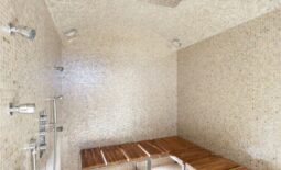 Sauna Shower with white mosaic tile, wooden bench, and many shower controls