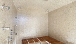 Sauna Shower with white mosaic tile, wooden bench, and many shower controls