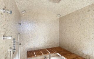 Sauna Shower with white mosaic tile, wooden bench, and many shower controls